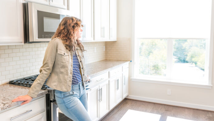 One,Young,Woman,Standing,In,Kitchen,In,Clean,,Modern,,White